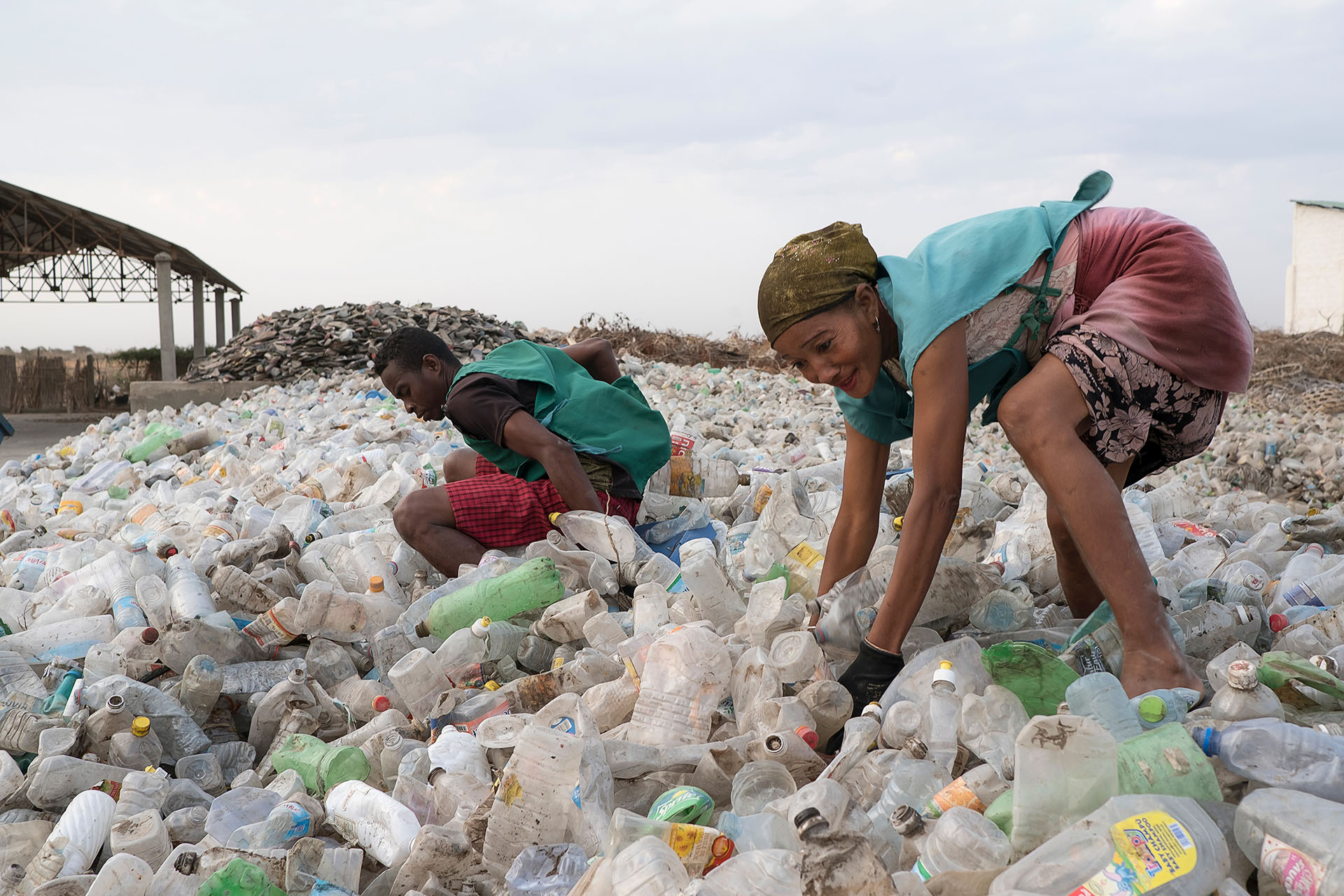 Zwei Personen stehen in einem Meer aus Plastikflaschen.