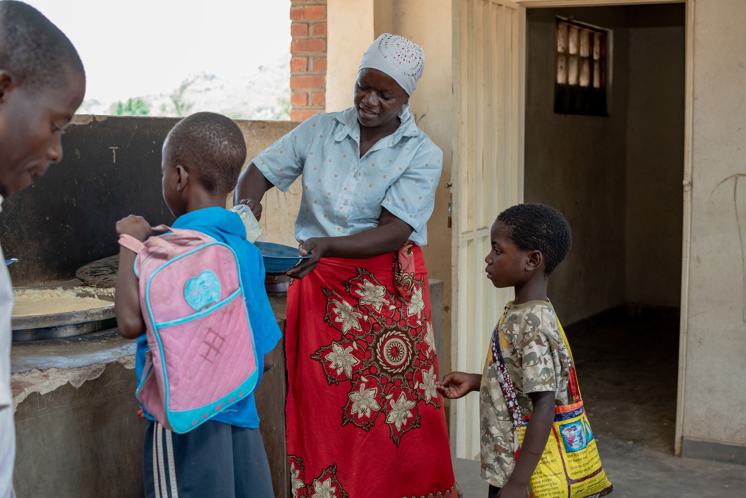Eine Frau schöpft für Kinder Essen auf ihren Teller