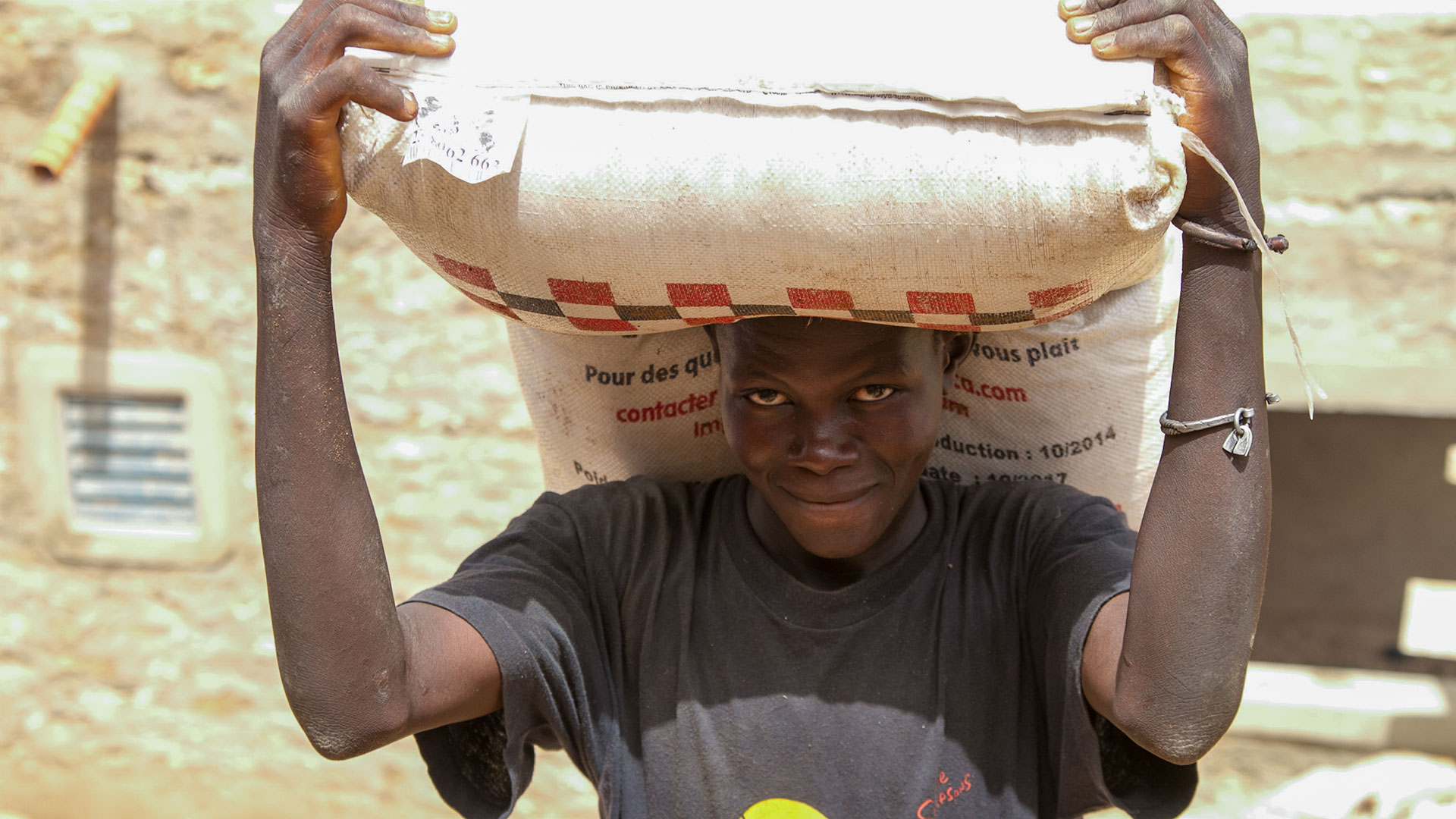 Ein Mann bei einer Nahrungsmittelverteilung hält einen großen Sack auf Kopf und Schultern. 