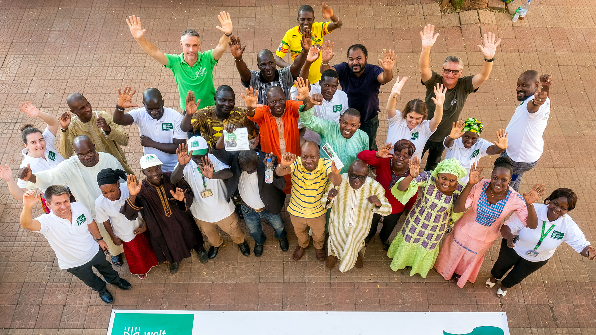 Eine Gruppe von Mitarbeiter*innen schaut Richtung Kamera und winkt