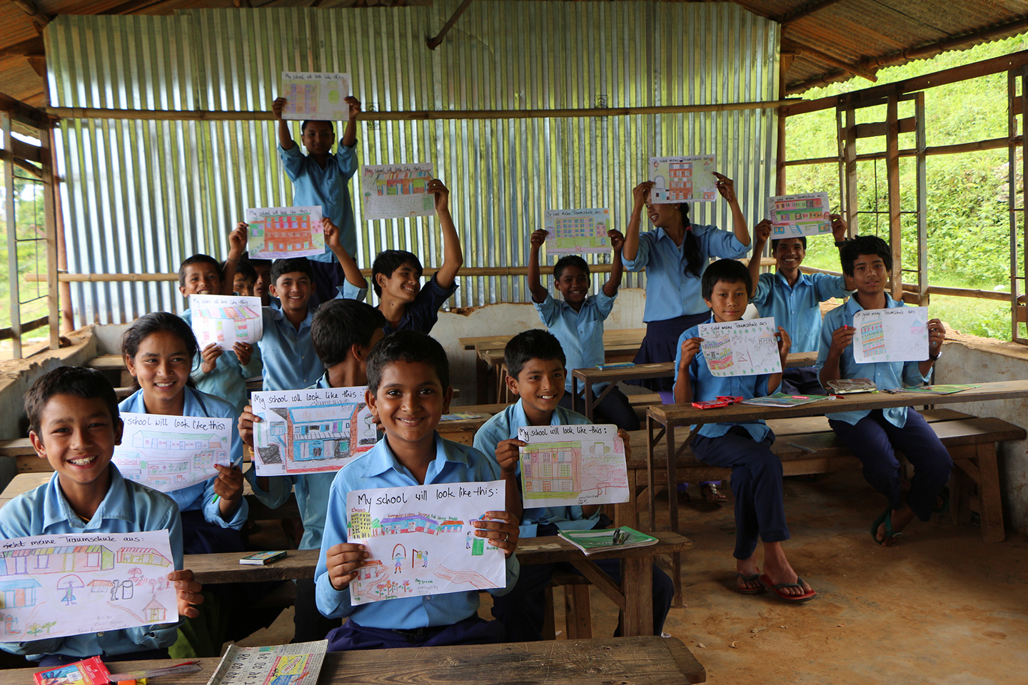 Kinder in einer Schule halten ihre selbstgemalten Bilder hoch