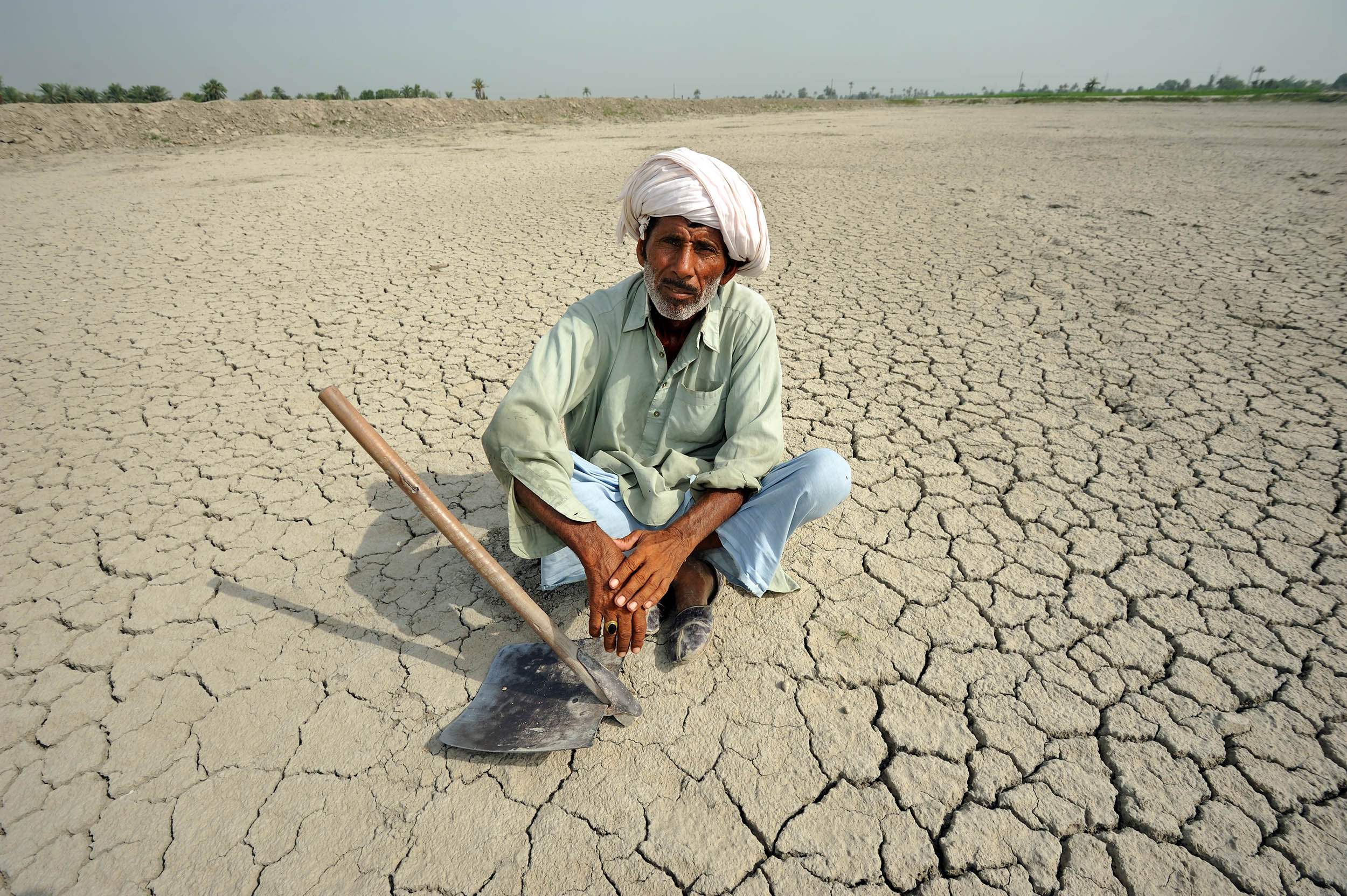 Ein Mann sitzt auf einem rissigen Boden, der die Folgen von Bodendegradation deutlich macht.