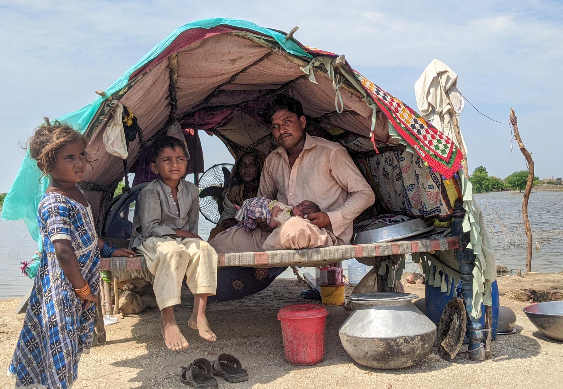 Ashok, Meena und ihre Familie müssen seit den Überschwemmungen auf der Straße leben. Während des Extremwetters kam auch ihr jüngstes Baby zur Welt. Meena wurde zur Entbindung in eine private Einrichtung gebracht, da sie bereits im Vorjahr eine Fehlgeburt hatte. Offenbar war sie schwach und unterernährt. Sie mussten ihre Ersparnisse einsetzen, um eine sichere Geburt in einer privaten Einrichtung in der Nähe zu bezahlen. Ihr Haus, ihr Hab und Gut und die chemische Reinigung, in der Ashok arbeitete, stehen unter Wasser, und sie konnten nicht viel von ihrem Besitz retten. Jetzt müssen sie auf der Straße leben, in einem provisorischen Zelt unter entsetzlichen Bedingungen, ohne sauberes Wasser, Toilette oder Waschgelegenheit. Sowohl Meena als auch ihr kleines Mädchen brauchen Pflege, die nicht zur Verfügung steht. 