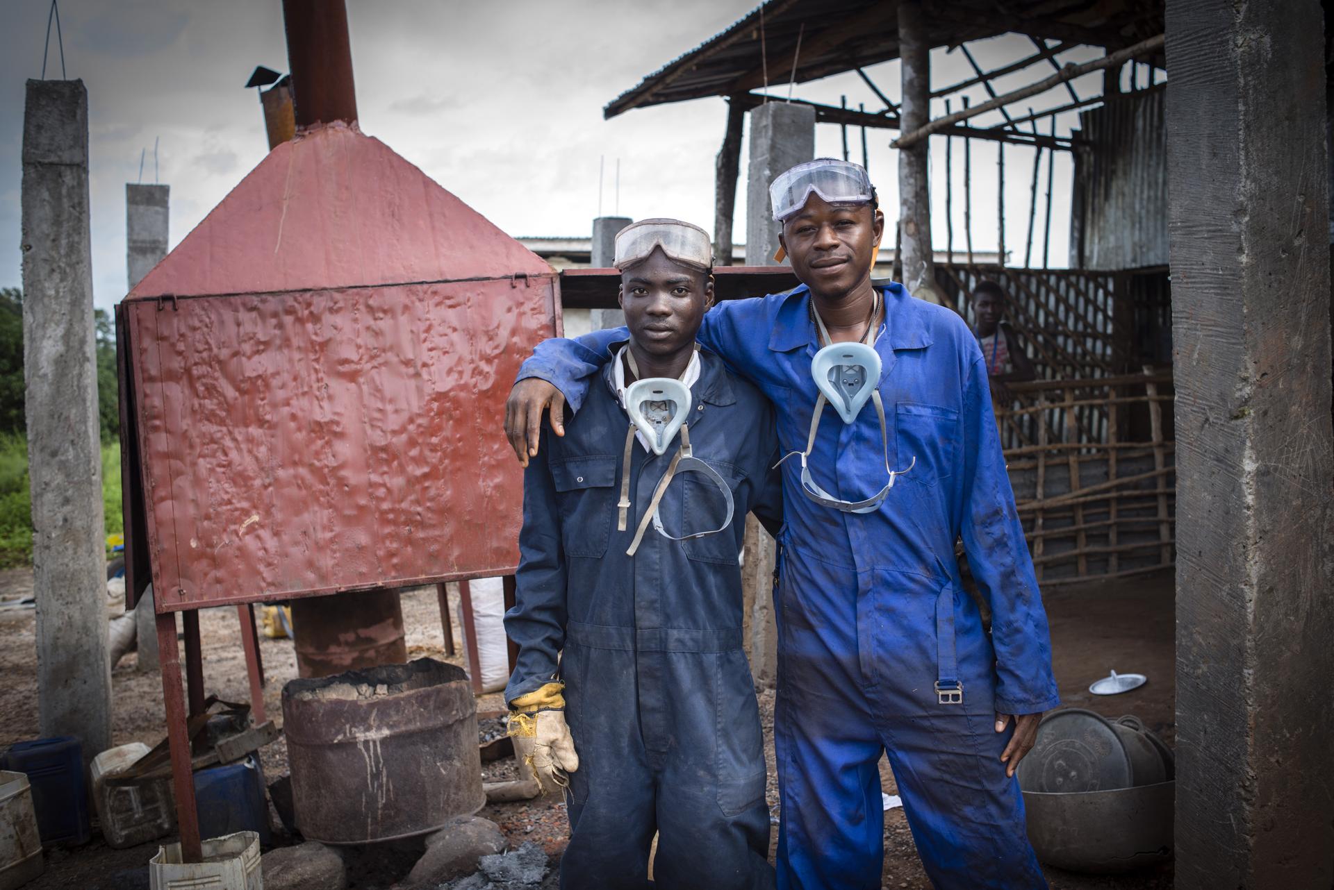 Zwei junge Männer in Arbeitskleidung, die ein Stipendium zur Produktion von Briketts erhalten haben.