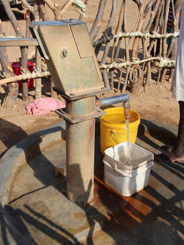 Ein Brunnen, aus welchem Wasser in einen Eimer läuft