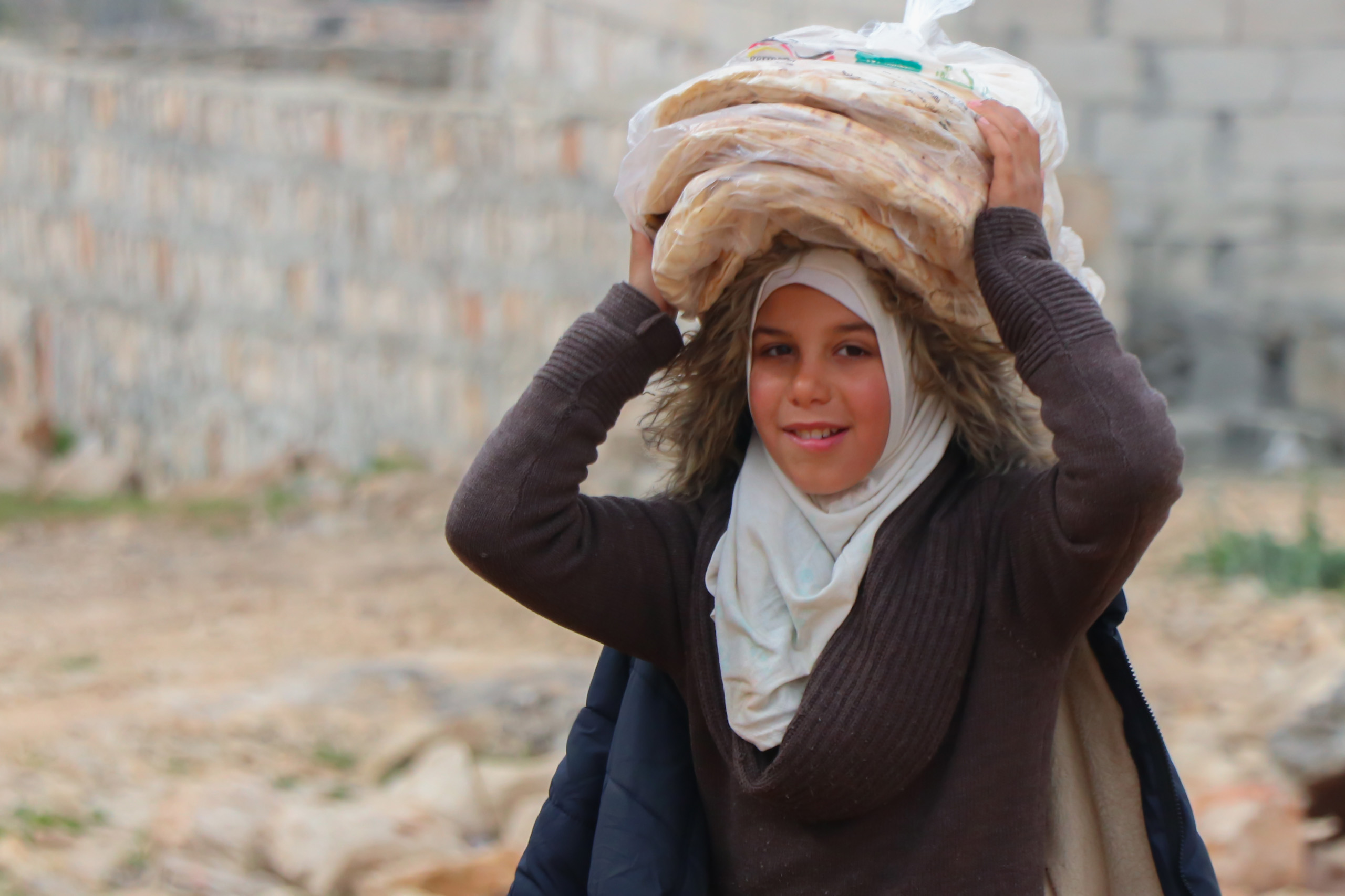 Spenden gegen Kälte und Hunger in Syrien: Ein syrisches Mädchen transportiert Brot auf ihrem Kopf 