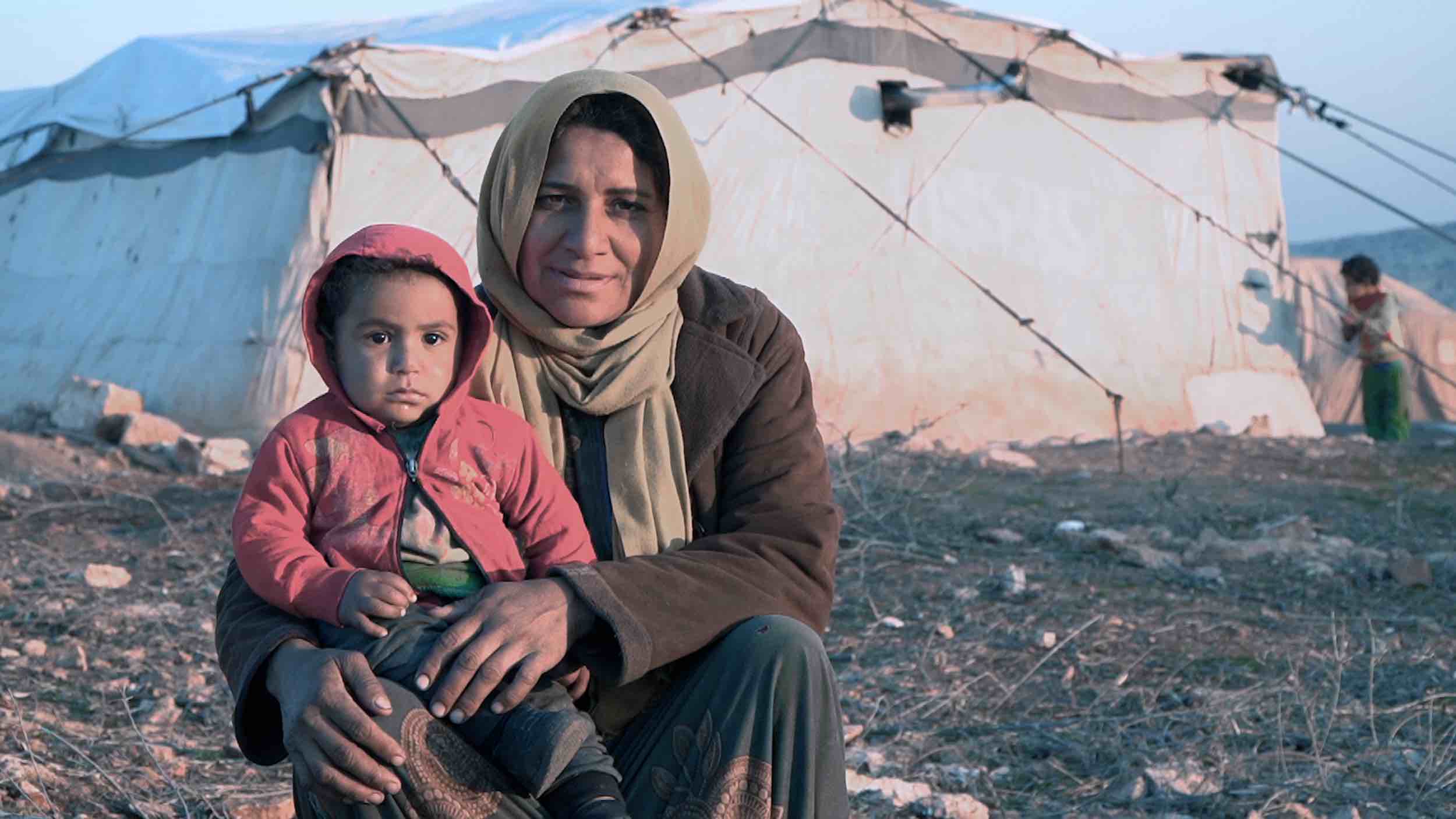 Winterhilfe in Syrien: Eine Mutter sitzt mit ihrem Kind auf der Erde