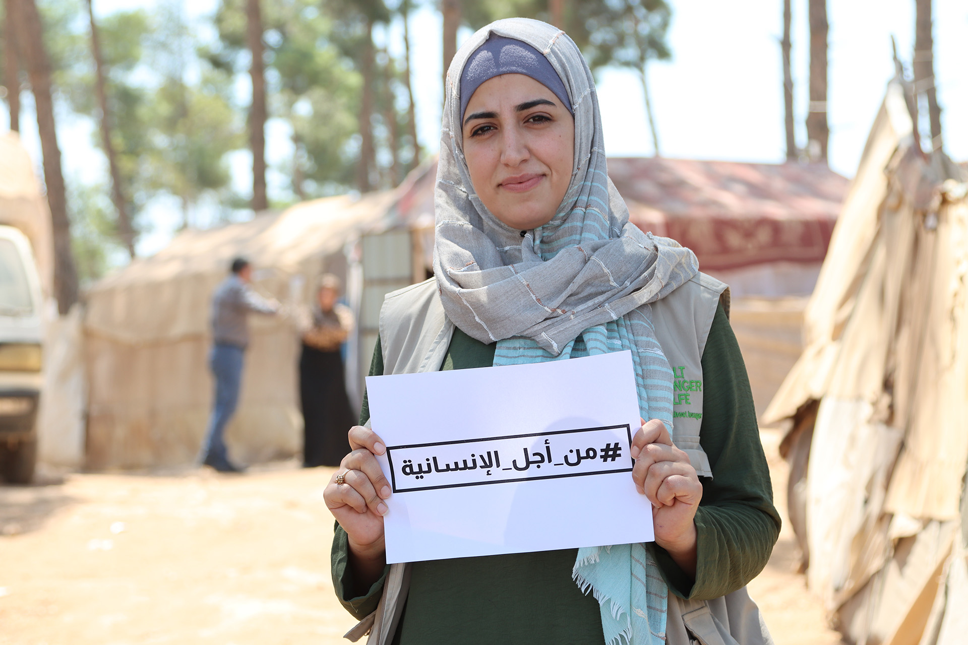 Frau in Syrien hält ein Schild mit einem Hashtag auf Arabisch
