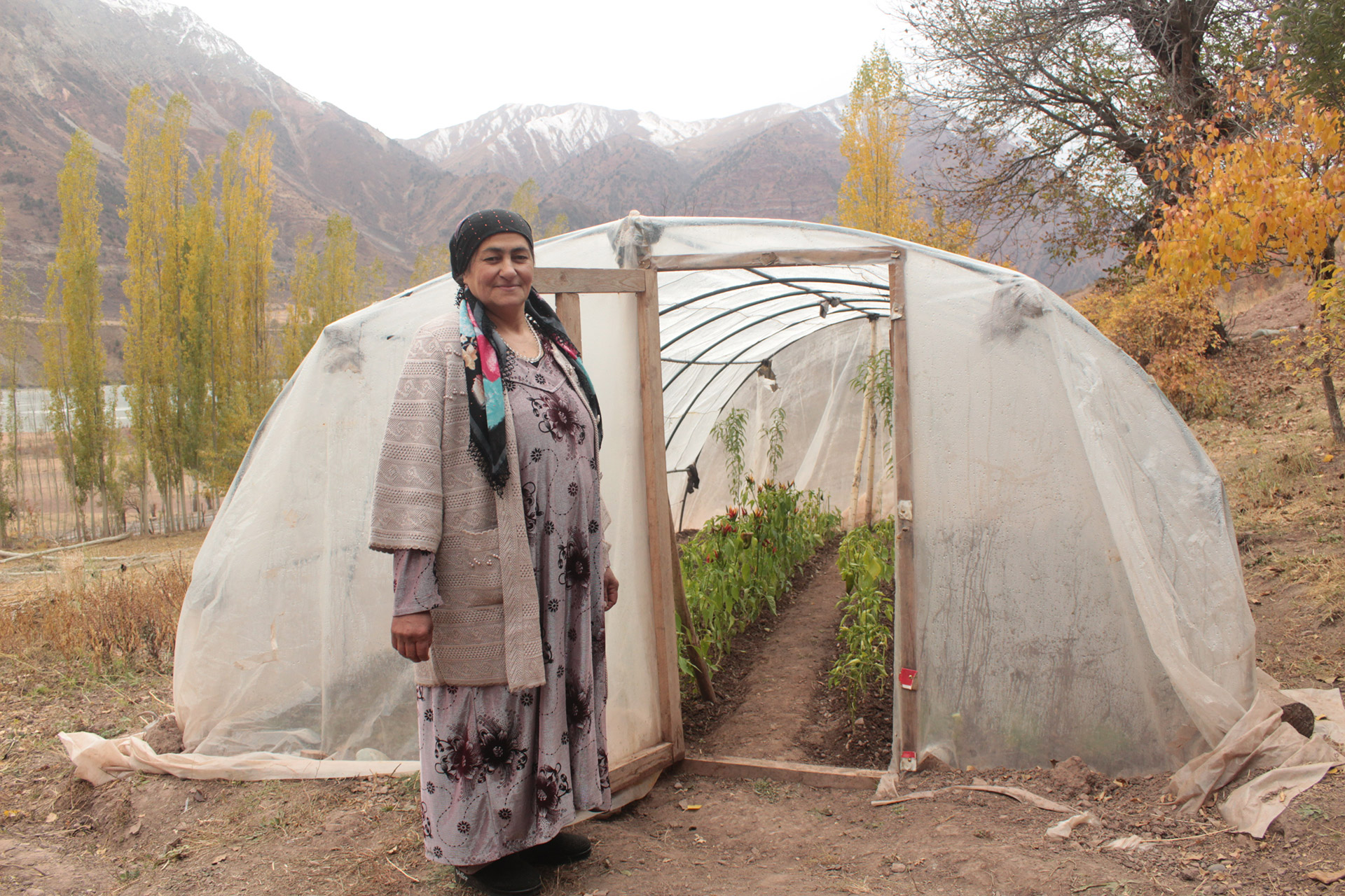 Eine Frau steht vor einem Gewächshaus in Tadschikistan, 2021.