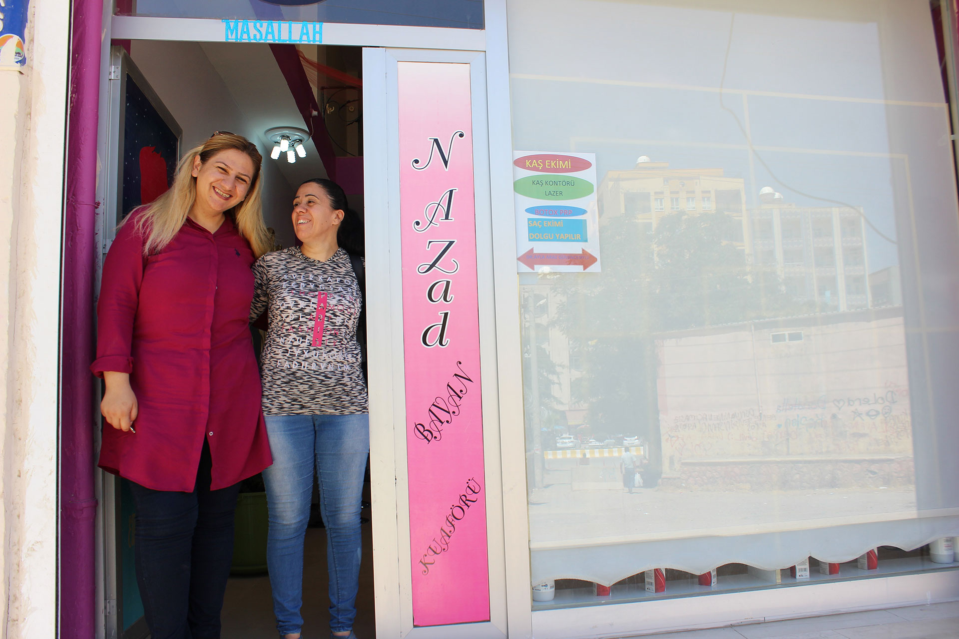 Zwei Frauen stehen lächelnd im Eingang eines Ladens.