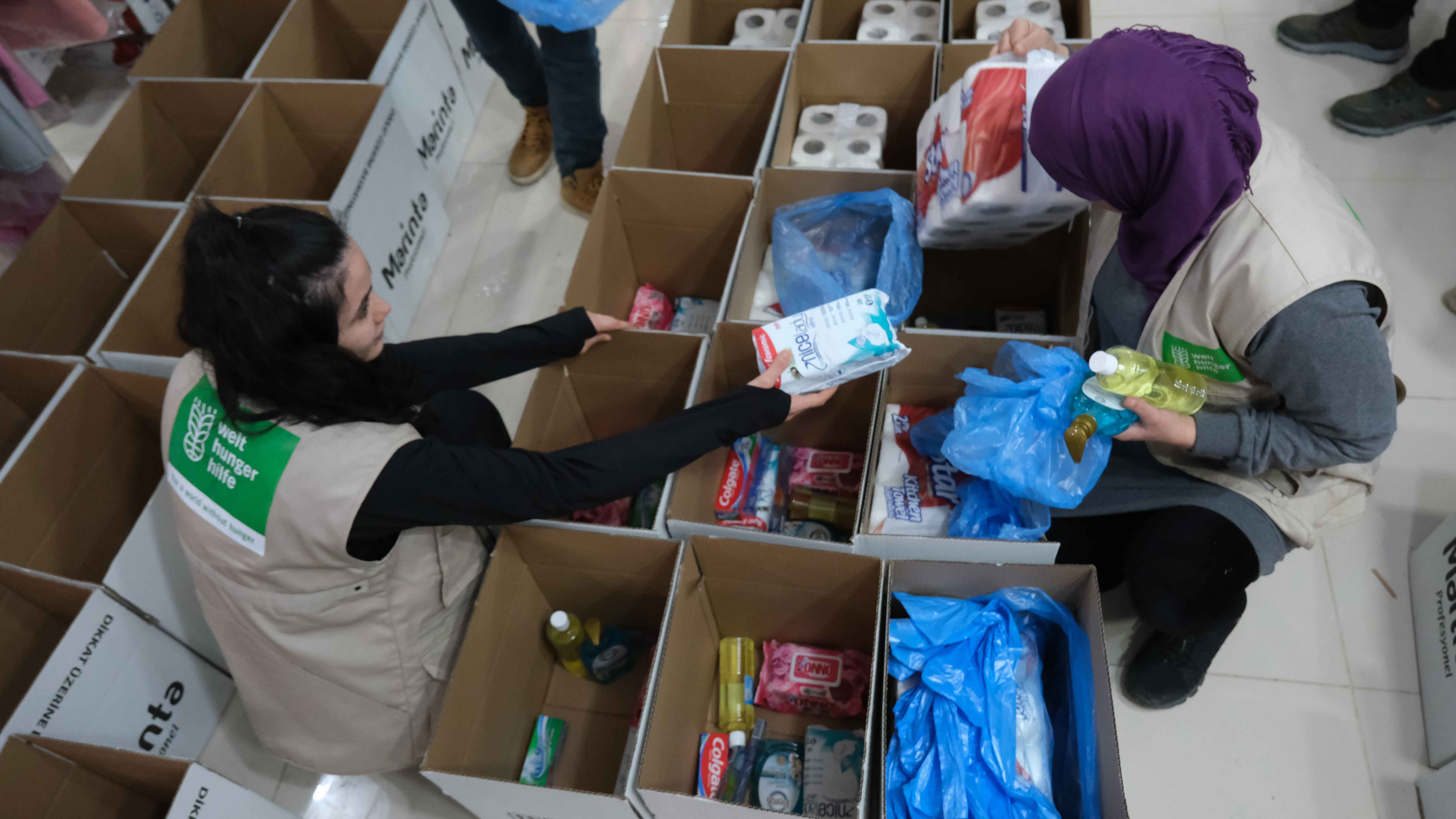 Zwei Frauen packen Hilfsgüter in Kartons.