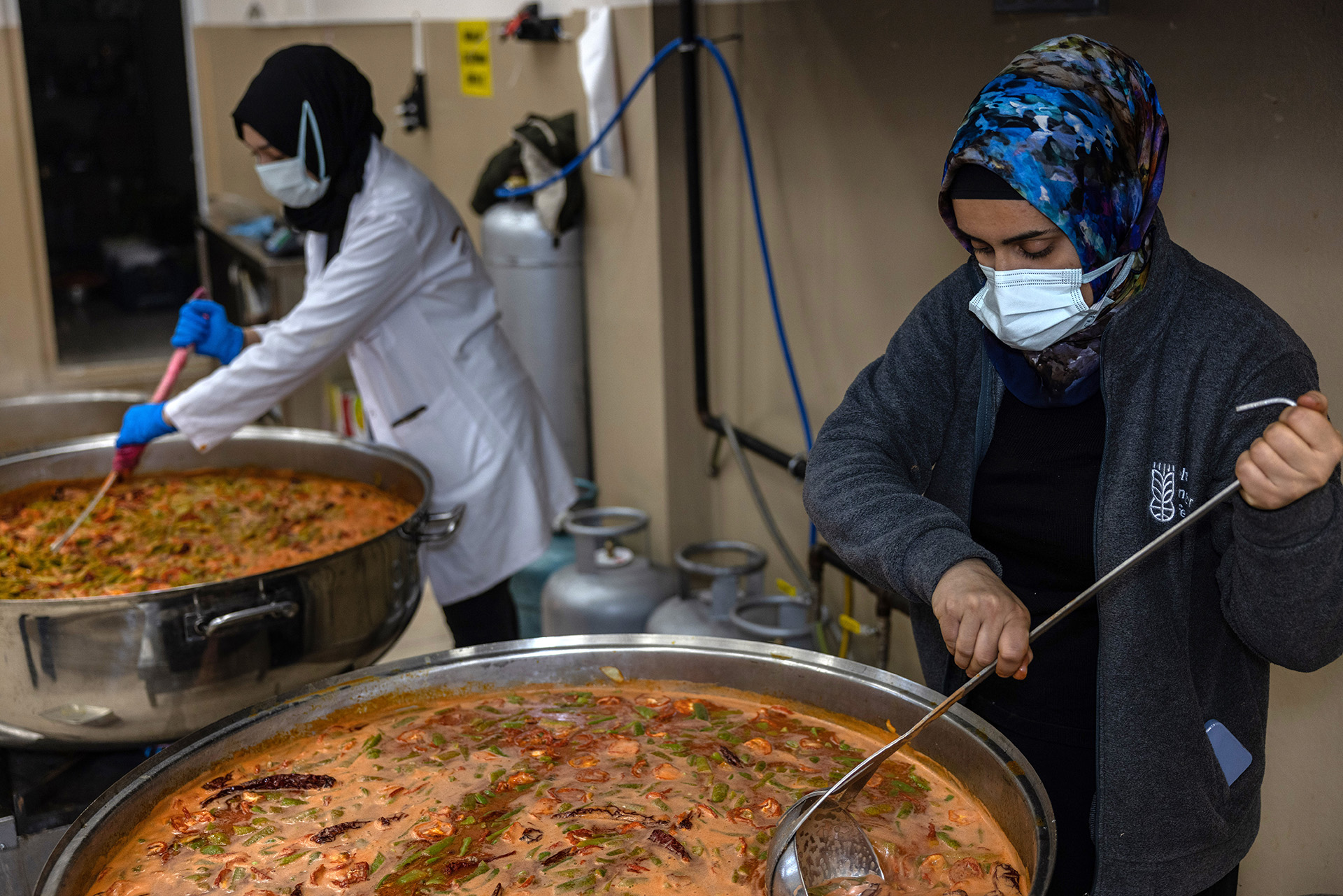 Zwei Frauen bereiten in großen Kochtöpfen Mahlzeiten für Erdbebenopfer zu.
