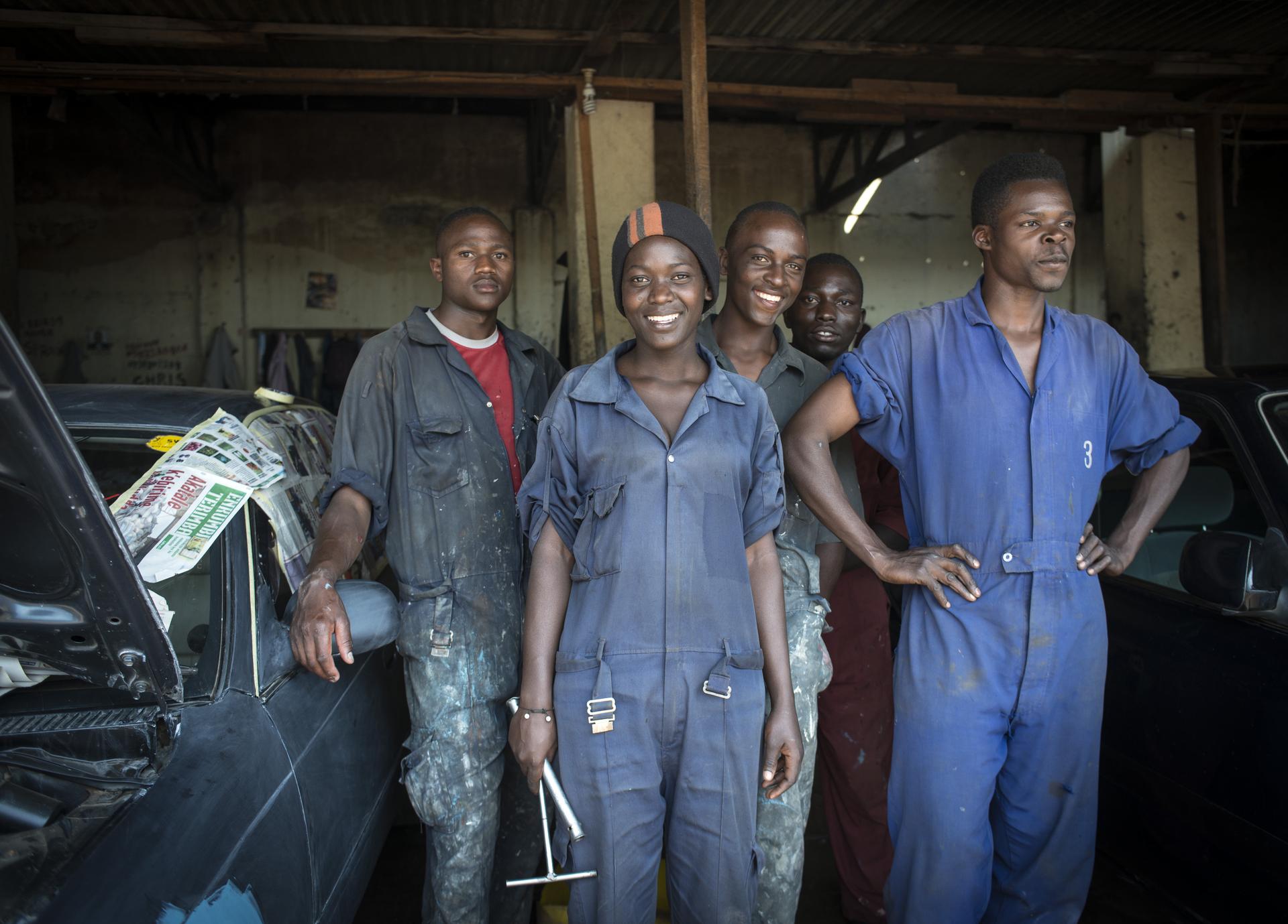 Jetzt als Unternehmen helfen. Bildbeschreibung: Eine Gruppe Jugendlicher in einer Autowerkstatt.