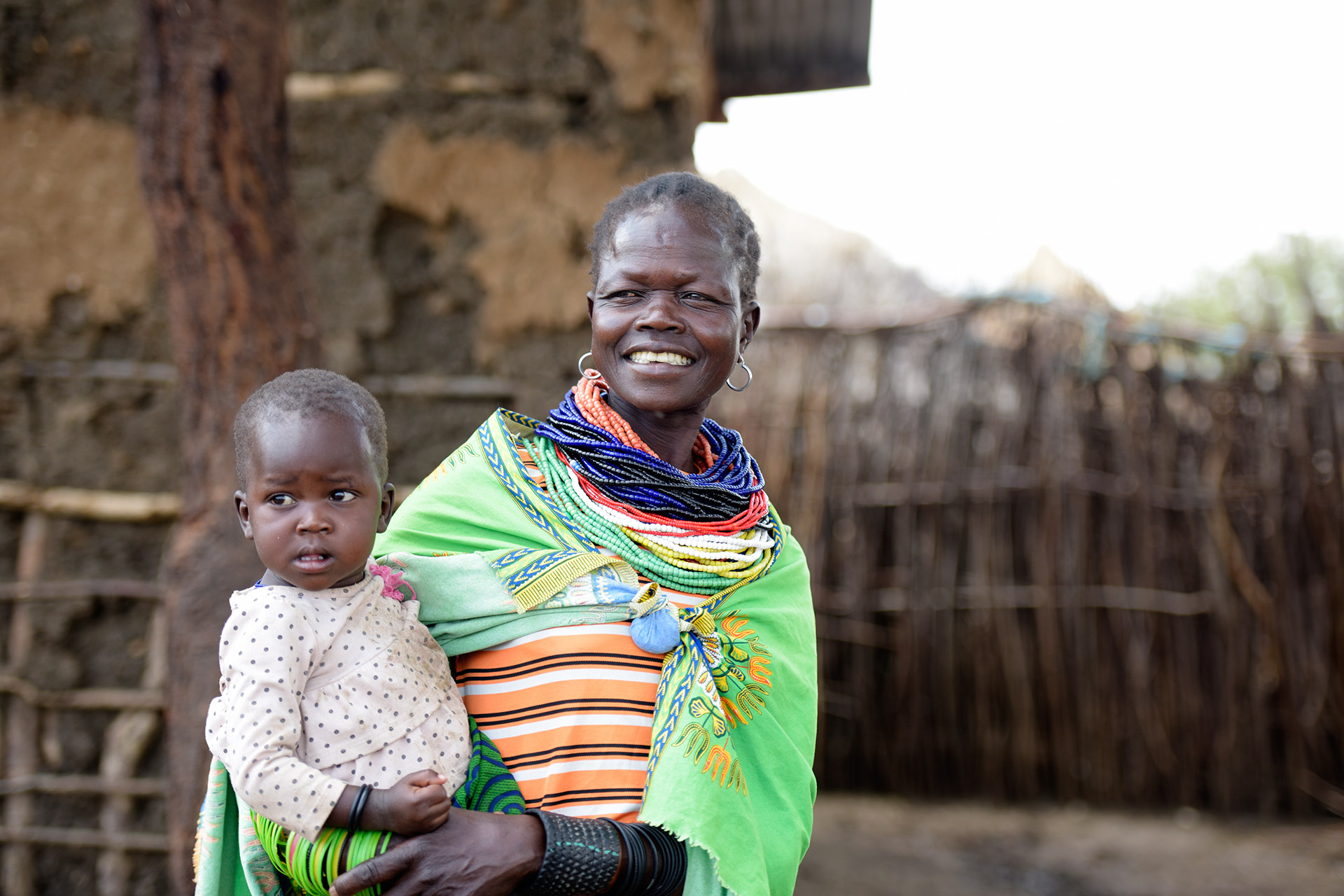 Eine lachende Frau mit einem Baby auf dem Arm.