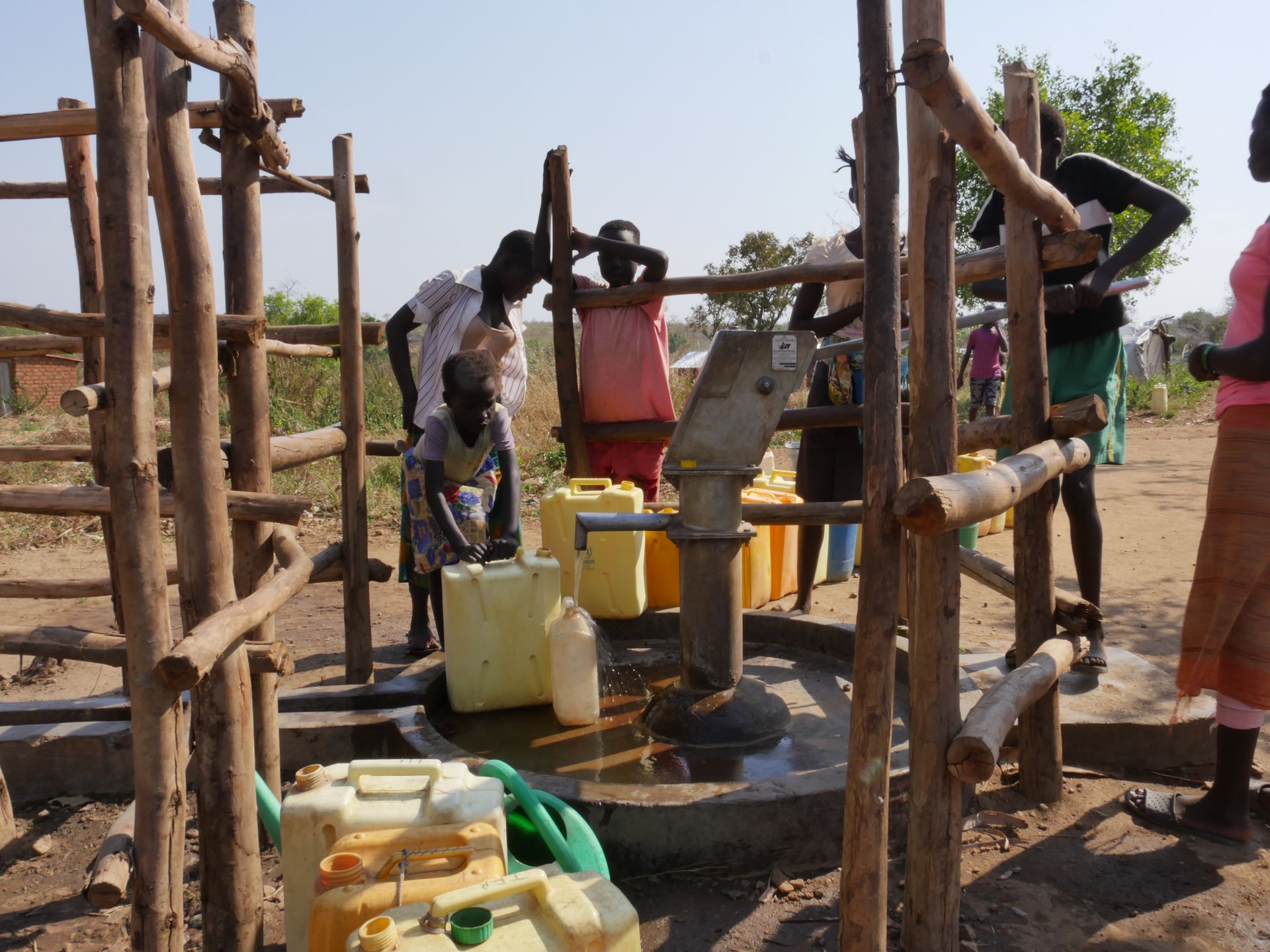 Menschen füllen an einem Brunnen Wasser ab