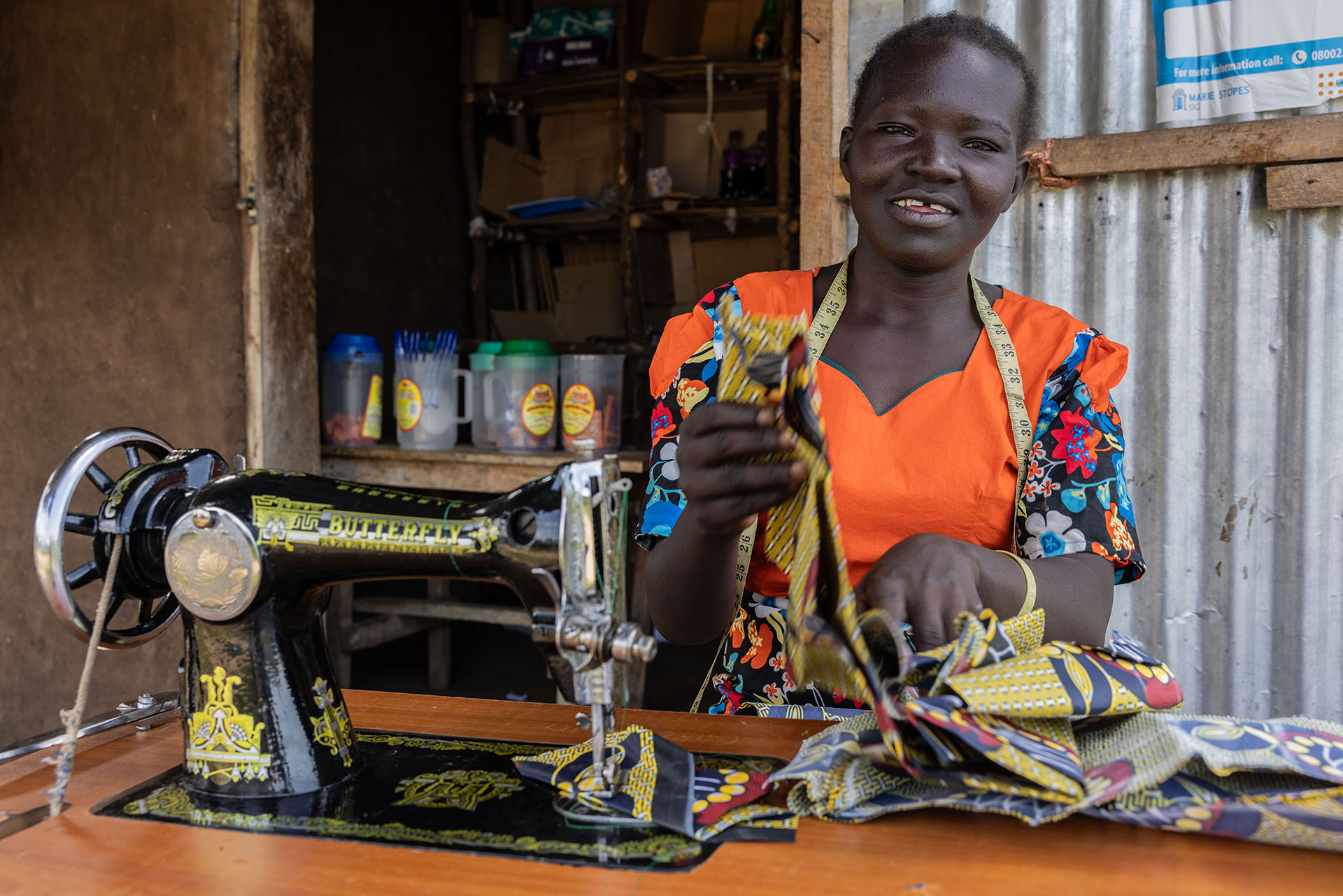 Frau sitzt lächelnd an ihrer Nähmaschine