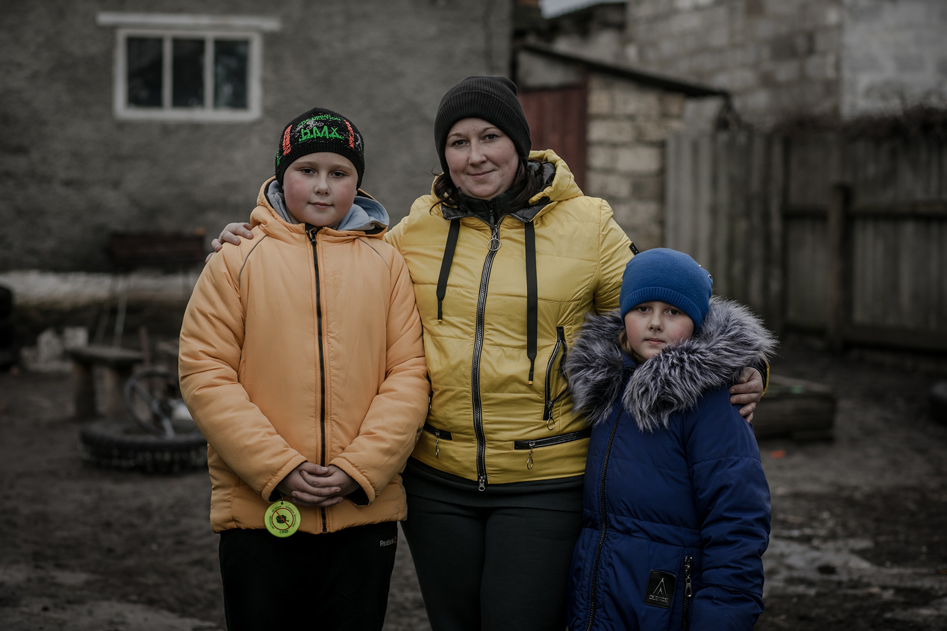 Eine Mutter und ihre beiden Kinder lächeln in die Kamera für eine Profilaufnahme