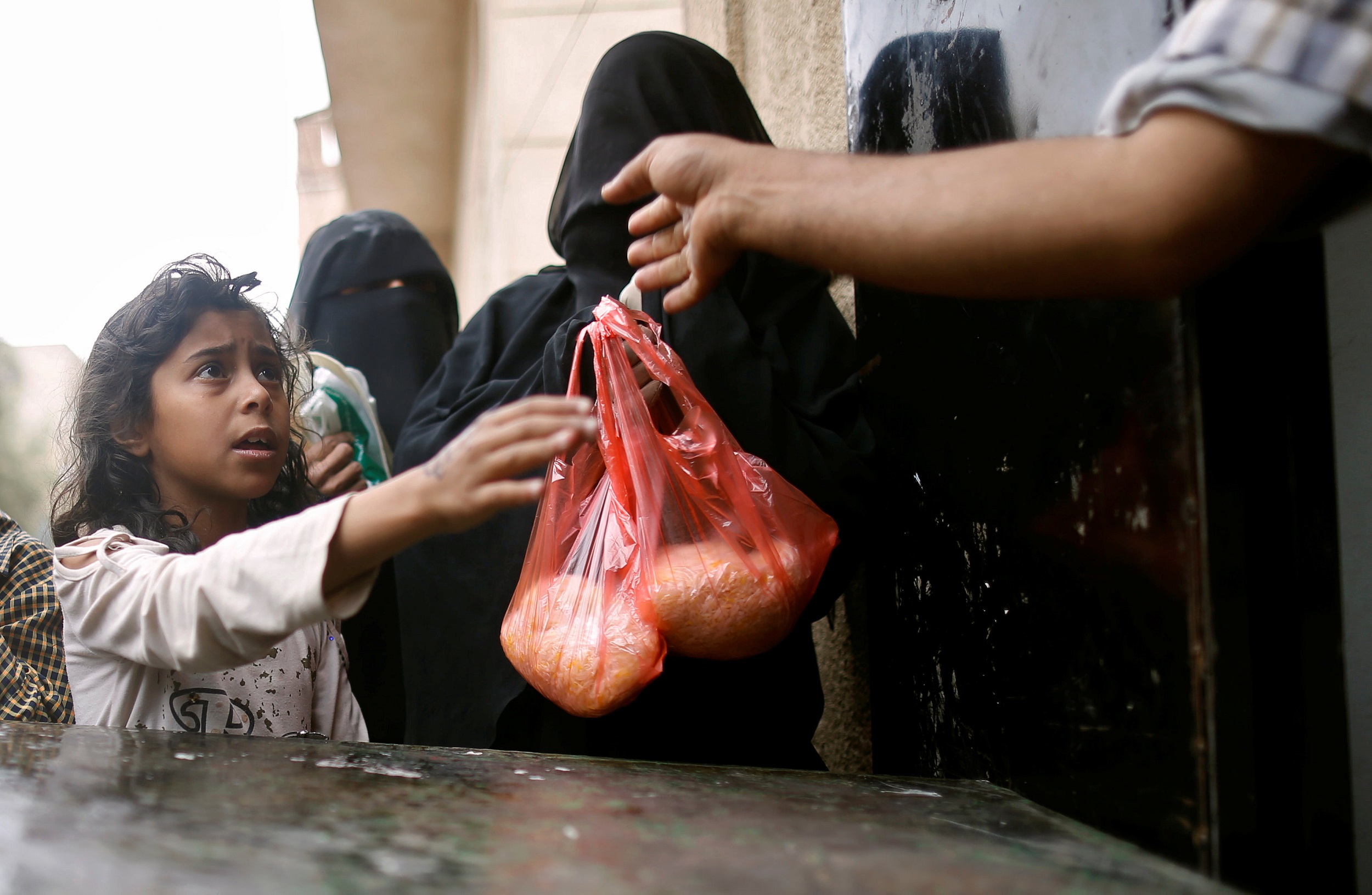 Ein Mädchen bekommt eine Tüte mit Reis.