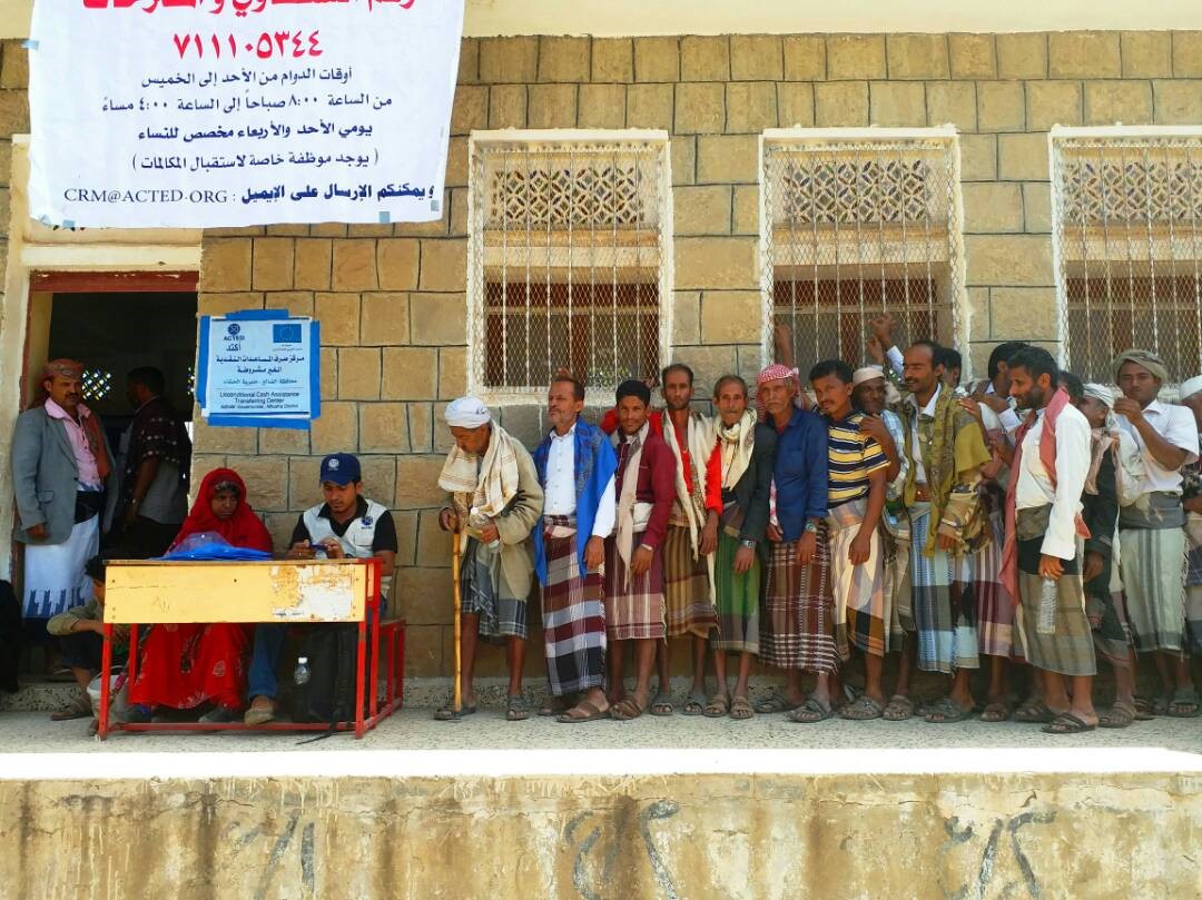 Menschen stehen bei einer Bargeldverteilung Schlange. 