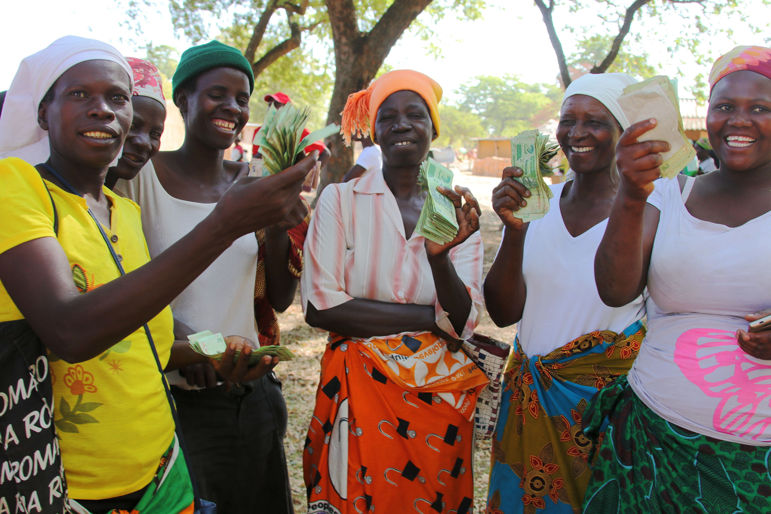 Fünf Frauen halten Geld in die Kamera, das sie als Kredit für ihre Unternehmensgründung erhalten haben.