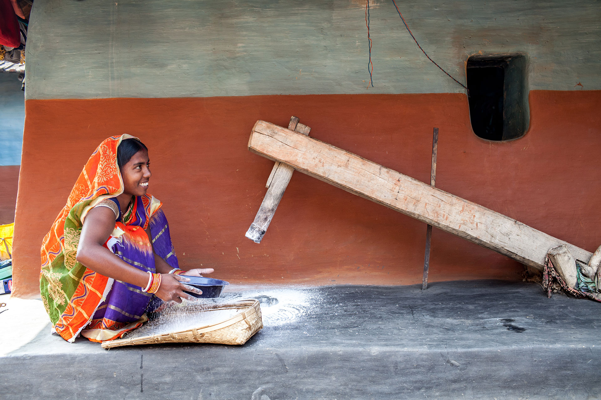 Malti Devi Gope (23) zerkleinert Reis in einem traditionellen Mahlstein in Huludbani, Jharkhand (Indien).