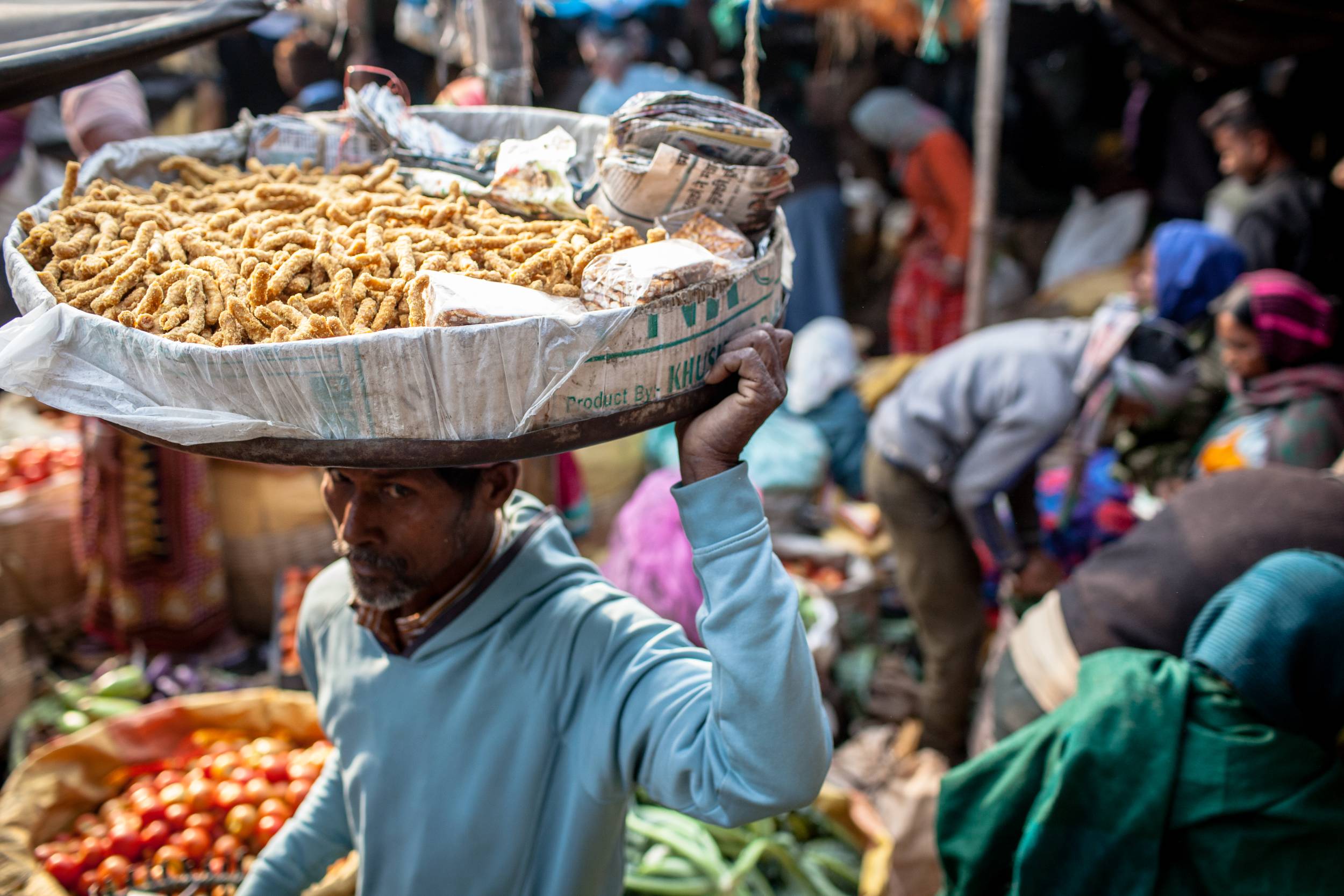 Ein Mann trägt einen großen Teller mit Essen auf dem Kopf bei einem Markt im indischen Jamshedpur. 
