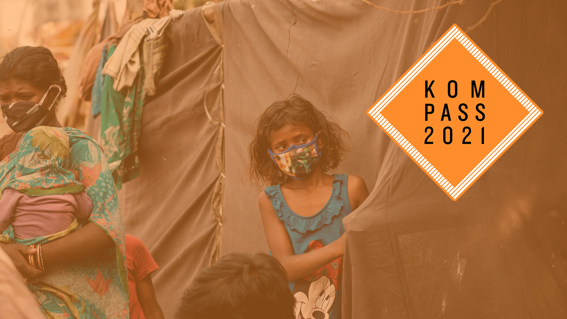 Ein Mädchen mit Maske steht vor einem Zelt.